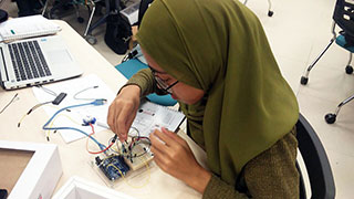 A participant from SMK Riam working on an Arduino kit.